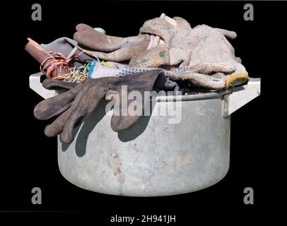 Schmutzige alte Arbeit benutzte Handschuhe in einem Küchentopf, der auf Schwarz isoliert war Stockfoto