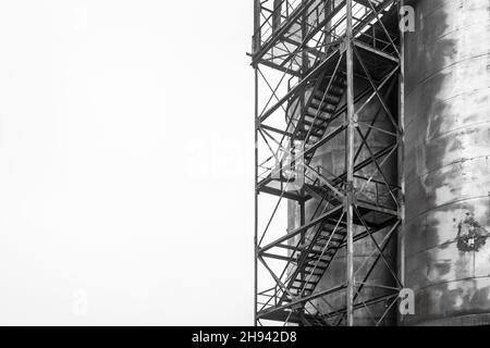 Altes Barrel-Öl für chemische Tanks in einer stillgelegten Industrieanlage anheizen. Leiter zu einer schmutzigen Zisterne. Stockfoto