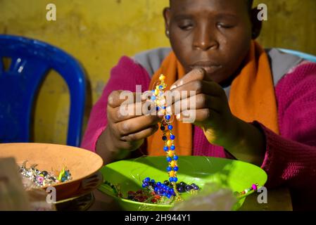 (211204) -- YAOUNDE, 4. Dezember 2021 (Xinhua) -- Ein blindes Mädchen stellt im Rehabilitationsklub für die blinde Jugend in Yaounde, Kamerun, ein Armband mit Perlen her, 29. November 2021. Menschen mit Behinderungen in Kamerun folgen verschiedenen Ausbildungs- und Sozialprogrammen in Institutionen wie der Fachschule für hörgeschädigte Kinder und dem Rehabilitationsklub für blinde Jugendliche, die ihnen helfen, sich wieder in die Gemeinschaft zu integrieren. Es gibt schätzungsweise 3,5 Millionen Menschen mit Behinderungen in Kamerun, und die Regierung war entschlossen, ihr Wohlergehen in der Gesellschaft zu gewährleisten, so der Minister für soziale Angelegenheiten des Landes Stockfoto