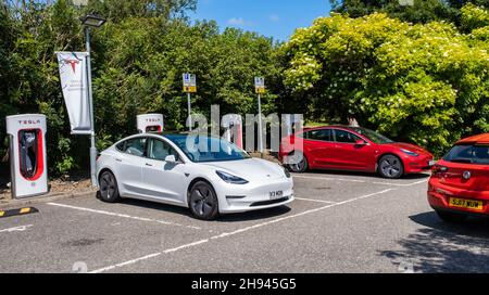 Abbington, Schottland - Juli 25th 2021 - Ein Tesla-Elektroauto wird an einer Tesla-Super-Ladestation geladen Stockfoto