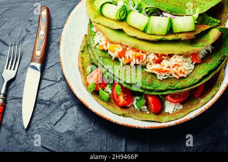 Pfannkuchen mit grünem Spinat, gefüllt mit Reis und Gemüse. Stockfoto