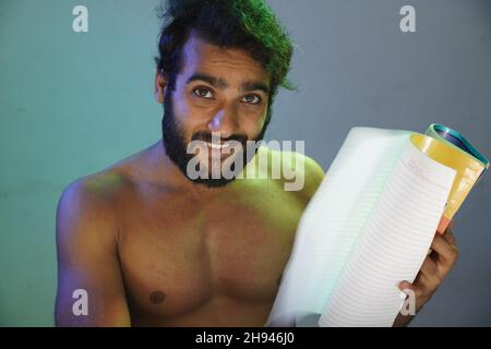 Der junge Schauspieler wird ein lächelndes Gesicht ohne Tücher im Studio schreiben Stockfoto