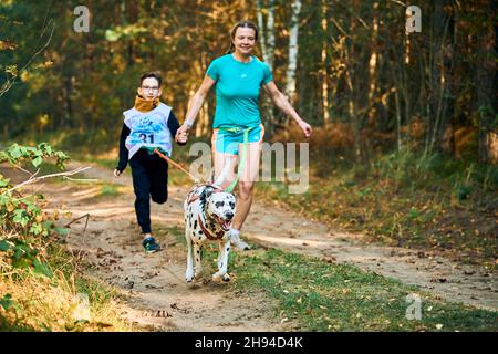 Svetly, Oblast Königsberg, Russland - 2. Oktober 2021 - Canicross-Übungen, Mutter und ihr Sohn laufen mit Händen am dalmatinischen Hund, Canicr Stockfoto