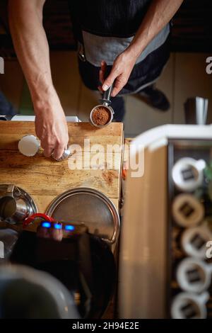 Ein Blick aus der Vogelperspektive auf die Hände des Barkeepers, der hinter der Bar in einer Arbeitsatmosphäre arbeitet. Kaffee, Getränke, Bar Stockfoto