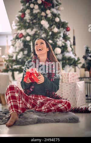 Mädchen feiern frohe Weihnachten zu Hause und genießen in den Ferien mit Geschenk Stockfoto