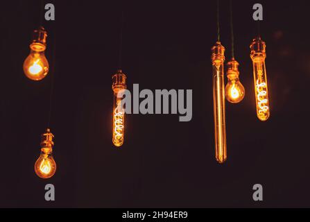 In der Dunkelheit der Nacht hängen schöne transparente Glaslampen und brennen mit einem angenehmen Licht. Dekorative Beleuchtung. Stockfoto