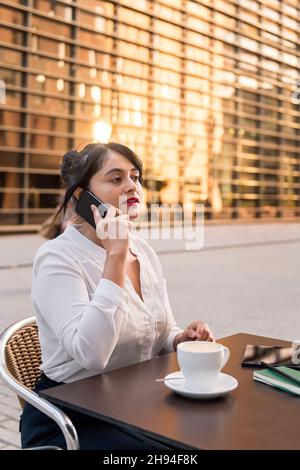 Geschäftsfrau im Telefongespräch auf der Terrasse eines Cafés, Konzept des digitalen Unternehmers und urbanen Lebensstils, Kopierraum für Text Stockfoto