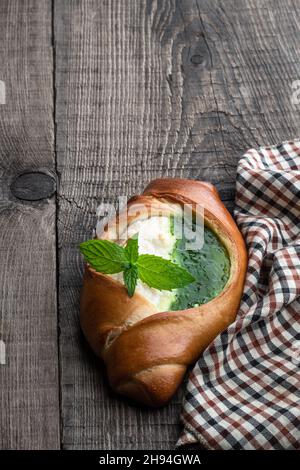 Frisch gebackenes Brötchen mit Quark und Kiwi-Marmelade auf Holztisch Stockfoto