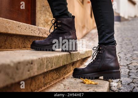 Modische schwarze Lederstiefel. Modische Schuhe aus nächster Nähe. Weibliche Beine auf der Treppe auf der Straße Stockfoto