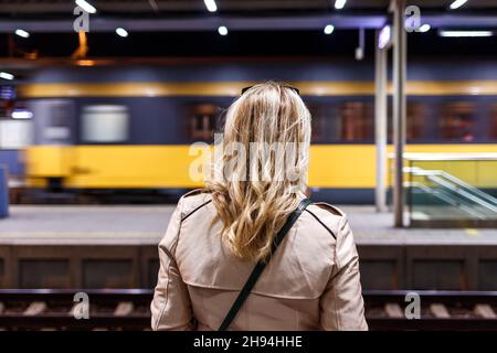 Frau, die am Bahnhof vorbeischaut. Öffentliche Verkehrsmittel. Anreise mit dem Zug. Nachtleben in der Stadt Stockfoto