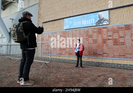 Ein junger Fan lässt sich vor einem Schild vor dem Boden fotografieren, in Erinnerung an den ehemaligen Manager von Coventry City, John Sillett, vor dem Sky Bet Championship-Spiel in der Coventry Building Society Arena, Coventry. Bilddatum: Samstag, 4. Dezember 2021. Stockfoto