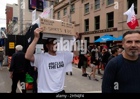 Melbourne, Australien, 4. Dezember 2021. Ein Mann, der Protesthemden in der Menge verkaufte, während der letzten „Aufhebung des Gesetzes“-demonstration von Tausenden Demonstranten vom parlamentsgebäude zur Flinders Street Station, um die Kreuzung zu halten. Demonstranten marschierten in den Büros des ABC- und Regierungshauses. Quelle: Michael Currie/Speed Media/Alamy Live News Stockfoto