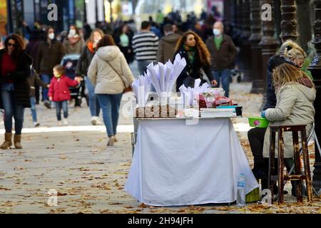 Granada, Spanien; 03. Dezember 2021: Frau verkauft gebratene Kastanienzapfen in einem Park in Granada (Spanien) bei Sonnenuntergang Stockfoto