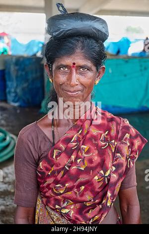 Kanaresen mittleren Alters (aus dem Bundesstaat Karnataka) auf einem Markt in Mangalore (Mangaluru), Karnataka, Südindien, mit einem kleinen Kauf auf dem Kopf Stockfoto