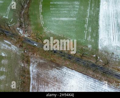 Sieversdorf, Deutschland. 04th Dez 2021. Nur wenig Schnee liegt auf den Feldern neben einer Straße im Bezirk oder-Spree im Osten Brandenburgs (Luftaufnahme mit Drohne). Quelle: Patrick Pleul/dpa-Zentralbild/dpa/Alamy Live News Stockfoto