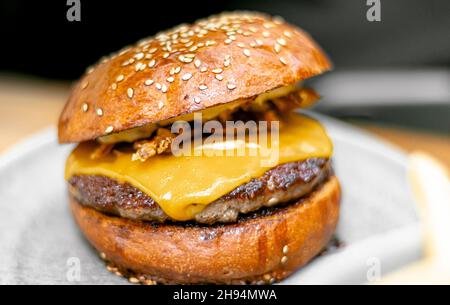 Craft Beef Burger mit Cheddar. Köstlicher Cheeseburger mit knuspriger Zwiebel auf einem Teller. Stockfoto