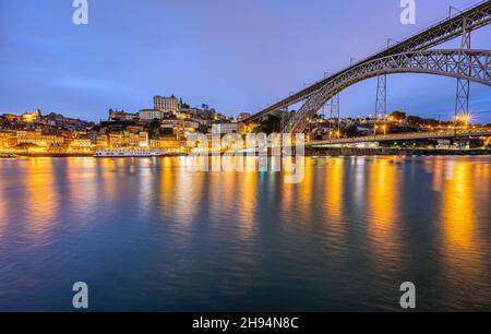 Die Altstadt von Porto mit dem Fluss Douro und der berühmten Eisenbrücke in der Abenddämmerung Stockfoto