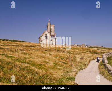 Menschen, die vom Dorf auf Lundy Island, Bristol Channel, Devon, England, Großbritannien, an der St. Helen's Church vorbeilaufen Stockfoto