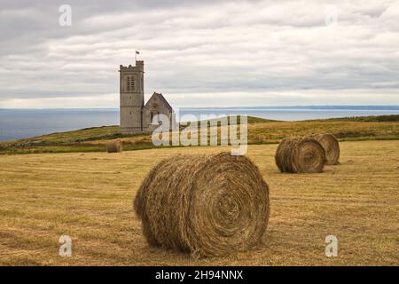 Runde Heuballen nach der Ernte auf dem Feld neben der St. Helen's Church auf Lundy Island, Bristol Channel, Devon, England, Großbritannien Stockfoto