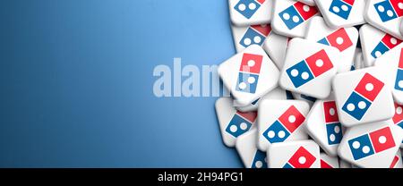 Logos der amerikanischen Pizza-Restaurantkette Domino's Pizza auf einem Haufen auf einem Tisch. Speicherplatz kopieren. Webbanner-Format. Stockfoto