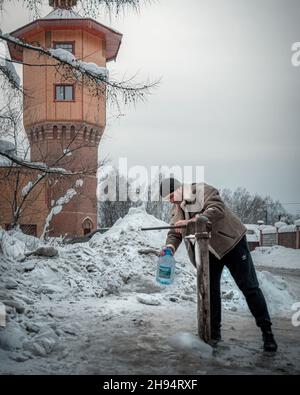 21st. Dezember 2019, Russland, Tomsk, die Wasserturm Handwasserpumpe, eine Person Stockfoto