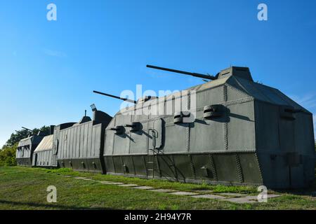 Ein grün gepanzerter Zug aus mehreren Wagen mit mehreren Kanonen und Maschinengewehren steht auf einem Hügel vor einem blauen Himmel Stockfoto