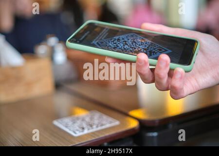 Nahaufnahme der Gäste, die eine Mahlzeit im Restaurant bestellen, während der QR-Code mit dem Mobiltelefon gescannt wird, um ein Online-Menü zu erhalten. Stockfoto