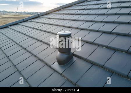 Nahaufnahme des Lüftungsrohrs auf dem Dach des Hauses, das mit Keramikschindeln bedeckt ist. Geflieste Abdeckung des Gebäudes. Stockfoto