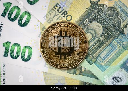 Bitcoin physische Münze, die auf 100 Euro-Scheinen liegt. Stockfoto