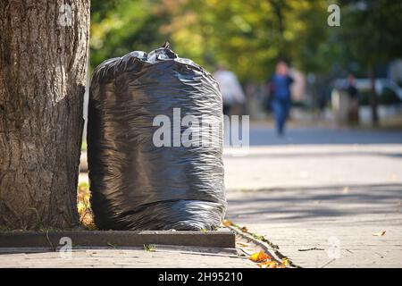 Stapel schwarzer Müllsäcke voller Müll, die auf der Straßenseite zur Abholung liegen. Abfallentsorgungskonzept. Stockfoto