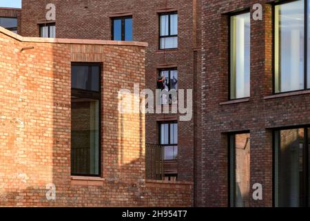 Fensterputzer bei der Arbeit (Abseiler, neue Wohnungen, Hochhaus-Apartmentgebäude, Sicherheit) - Hudson Quarter, York City Centre, North Yorkshire, England Großbritannien. Stockfoto