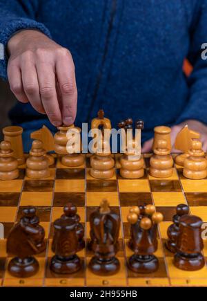 Nahaufnahme eines Mannes, der Schach auf einem alten Holzschachbrett spielt Stockfoto