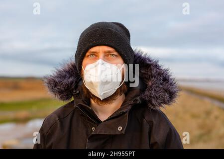 Ein junger Mann, der während der Corona-Pandemie des Covid-19-Virus eine Gesichtsmask mit einer KN95-1-Anwendung trägt Stockfoto