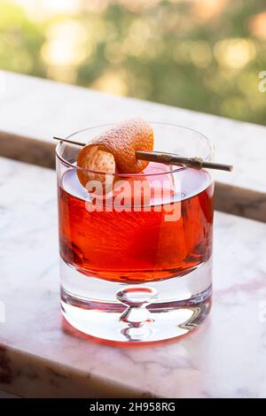 Negroni Bitter Cocktail Drink mit Orange Twist Over Ice in Rocks Glass in Marmor Fensterbank Stockfoto