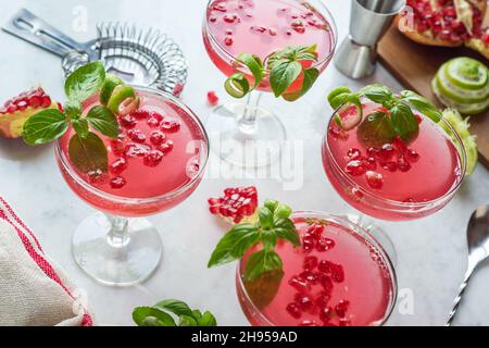 Granatapfel Basil Martini Cocktails mit Limette Twist in Coupé Gläser auf Marmor Theke Stockfoto