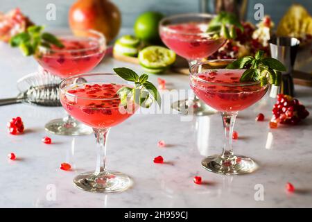 Granatapfel Basil Martini Cocktails mit Limette Twist in Coupé Gläser auf Marmor Theke Stockfoto