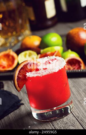 Blutorange Margarita auf den Felsen mit gesalzenem Rand und Zutaten im Hintergrund Stockfoto