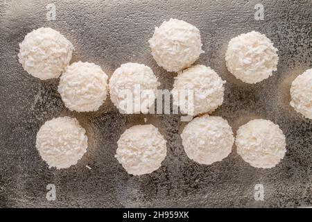 Mehrere leckere Süßigkeiten mit Kokosflocken auf einem Metalltablett, Nahaufnahme, Draufsicht. Stockfoto