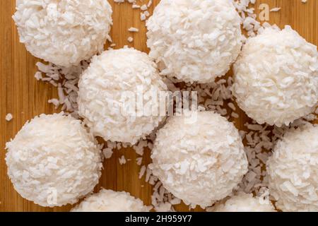 Mehrere süße, köstliche Pralinen mit Kokosflocken auf einem Bambusblech, Nahaufnahme, Draufsicht. Stockfoto