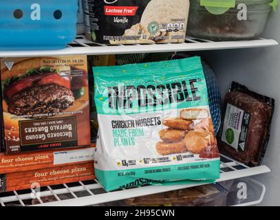 MORGANTOWN, WV - 4. November 2021: Verpackung für Impossible Foods Chicken Nuggets im heimischen Gefrierschrank neben Büffelburgern Stockfoto