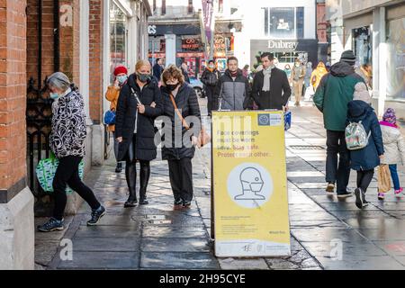 Cork, Irland. 4th Dez 2021. Auf dem englischen Markt in Cork, auf dem angegeben ist, dass Gesichtsbezüge getragen werden müssen, laufen Menschen an einem COVID-19-Schild vorbei. Die Regierung hat bis zum 9th. Januar Beschränkungen für die Bewirtung und das Vermischen von Haushalten auferlegt. Quelle: AG News/Alamy Live News Stockfoto