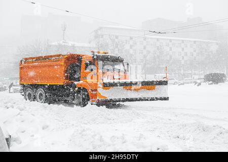 Ein großer orangefarbener Schneepflug steht auf der Straße, bevor Schnee entfernt wird. Sonderausrüstung für Schneeräumungszyklon. Stockfoto