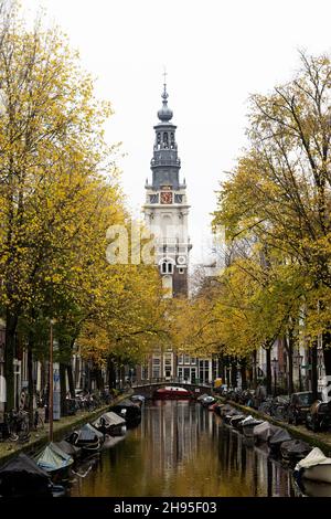Der Blick von der Staalmeesterbrücke auf den Kanal bei Groenburgwal in Amsterdam, Niederlande, mit Blick auf den Zuiderkerk-Turm an einem Herbsttag. Stockfoto