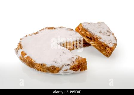 Panforte von Siena, traditioneller Weihnachtskuchen mit Mandeln, Orangenschalen und Gewürzen aus der toskana, italien. Kuchen mit Scheibe isoliert auf weiß Stockfoto