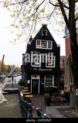 Das Café de Sluyswacht, ein berühmtes, gelehntes ehemaliges Schlossgebäude aus dem Jahr 1695 in der Jodenbreestraat am Kanal in Amsterdam, Niederlande. Stockfoto