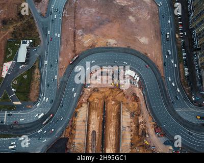 Bau eines Tunnels unter der Autobahn. Bau einer Verkehrsknotenstelle. Drohnenansicht. Umleitungen der Baustelle. Stockfoto