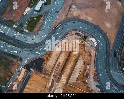 Bau eines Tunnels unter der Autobahn. Bau einer Verkehrsknotenstelle. Drohnenansicht. Umleitungen der Baustelle. Stockfoto