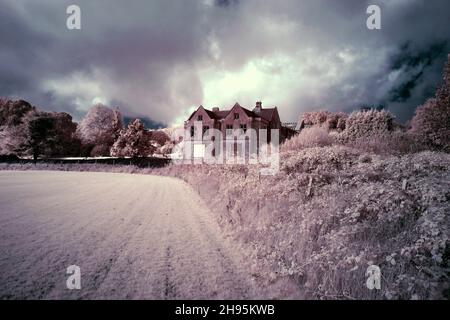 Unbefestigte Straße führt zu einem verlassenen Privathaus gegen den bewölkten Himmel in rosa Farben Stockfoto