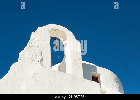 Glocke und Mond durch einen Gebäudebogen in Mykonos, Griechenland Stockfoto