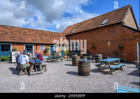 Eine Gruppe von Freunden, die im Biergarten vor der Sixpenny Brewery auf der Holwell Farm in der Nähe von Wimborne, Dorset, England, Bier trinkt. Stockfoto